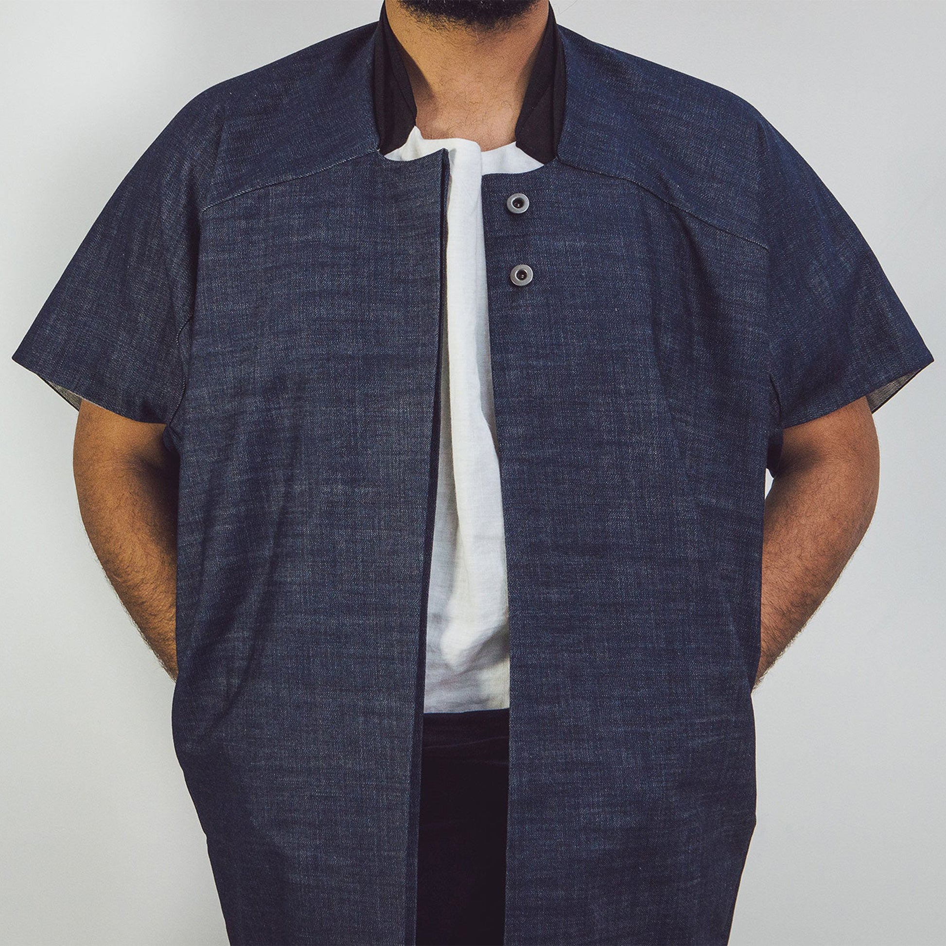 Man wearing The Costume Room Raw Organic Denim Cocoon Long Jacket with hands in pockets