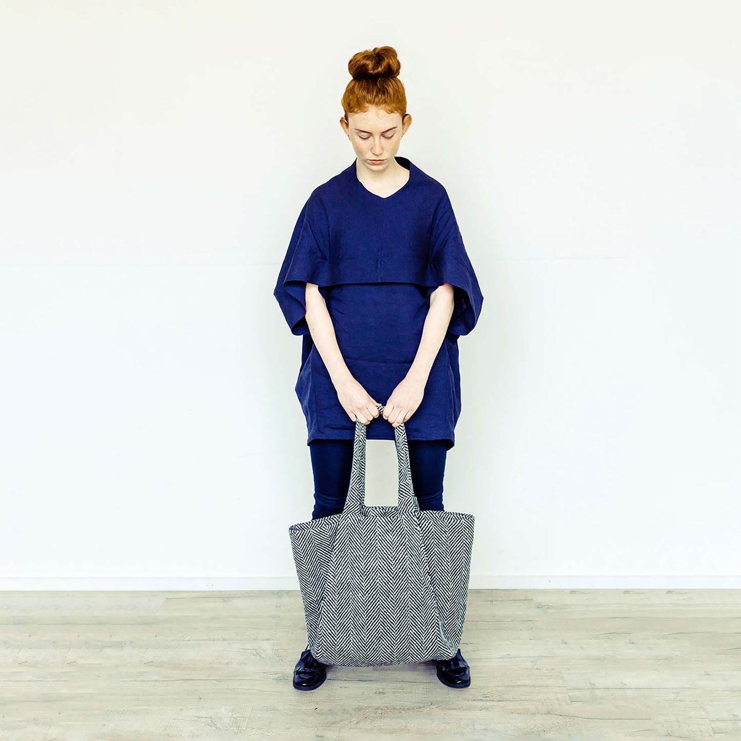 Woman wearing The Costume Room navy linen top and monochrome herringbone Handwoven Donegal Tweed Bag