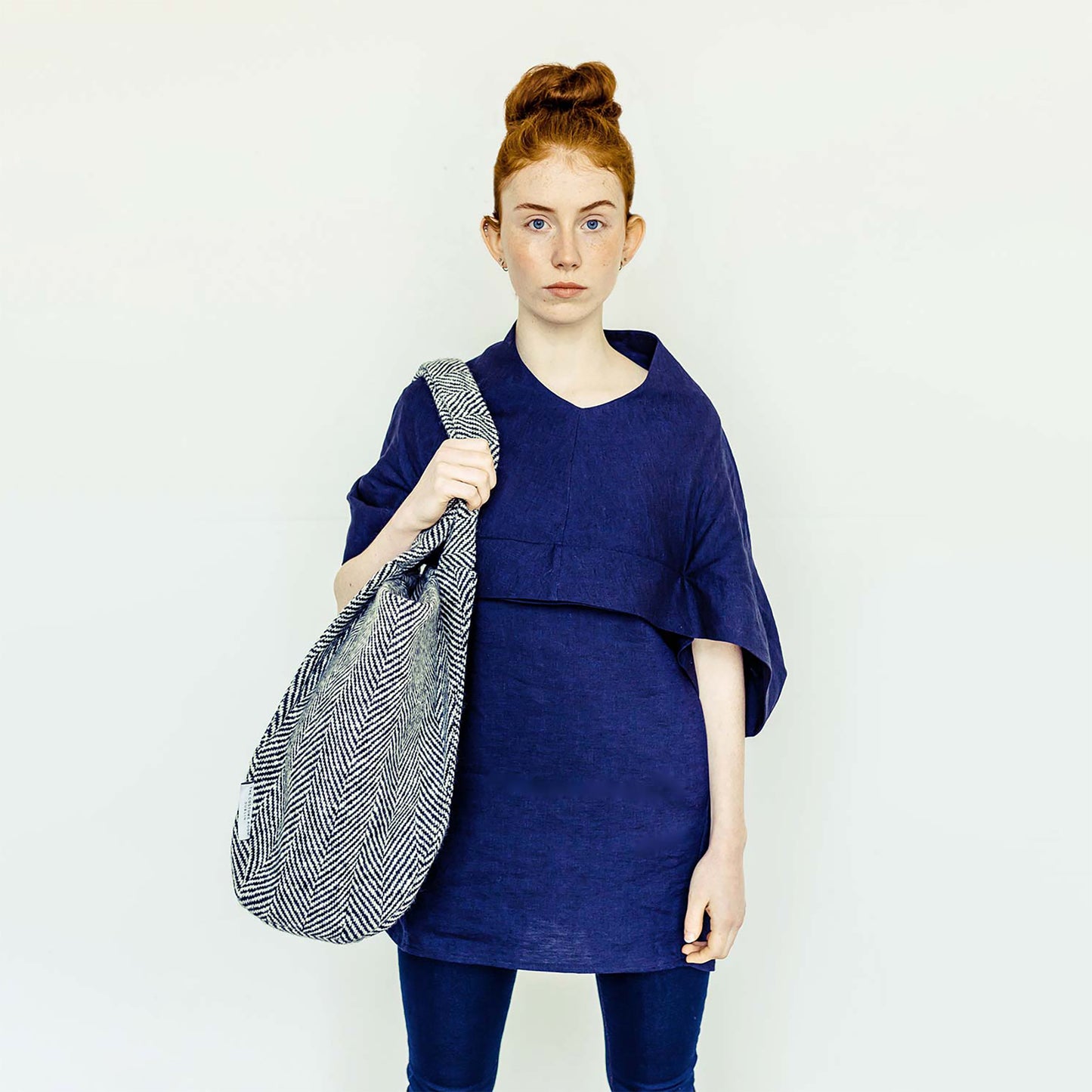 Woman wearing The Costume Room navy linen top and monochrome herringbone Handwoven Donegal Tweed Bag