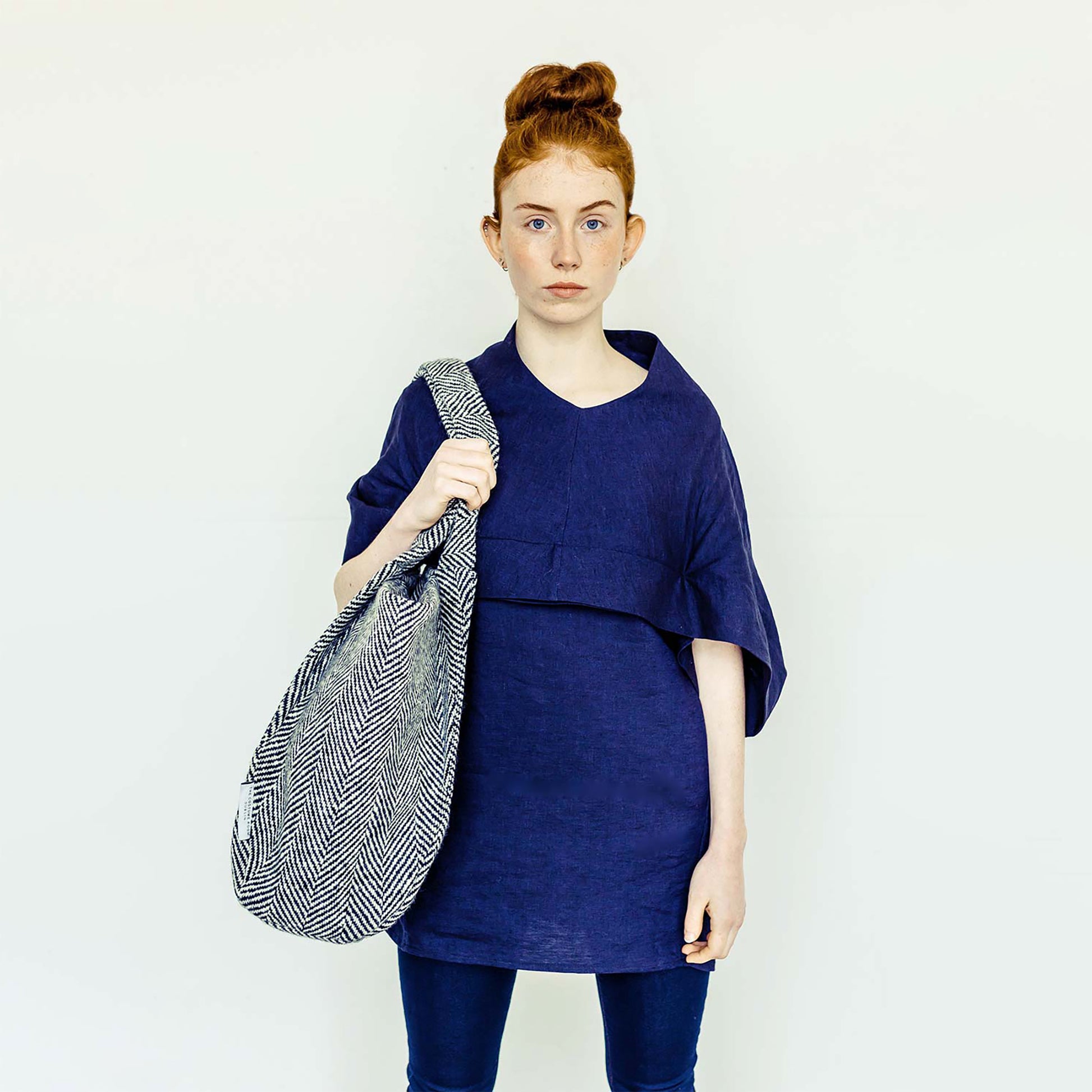 Woman wearing The Costume Room navy linen top and monochrome herringbone Handwoven Donegal Tweed Bag