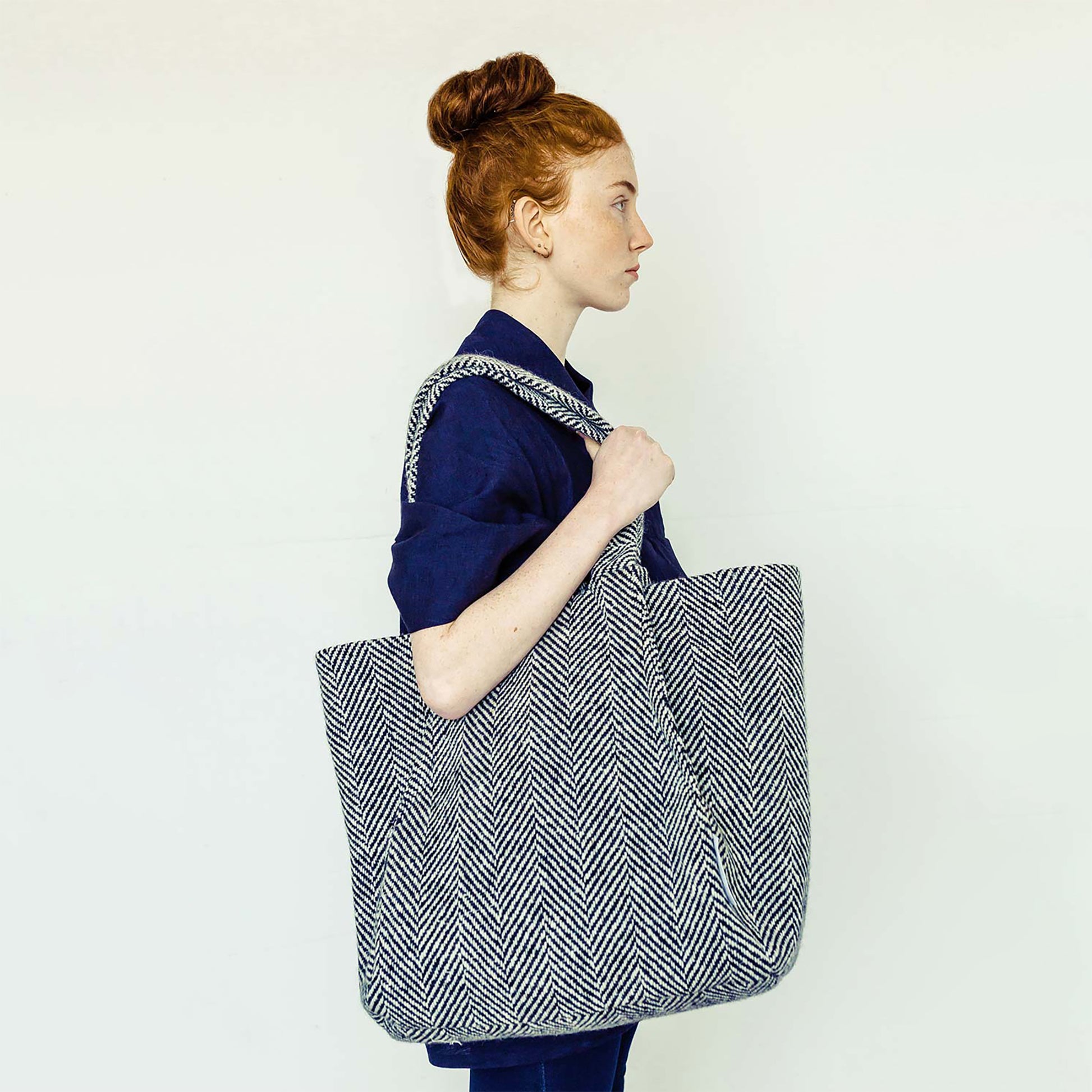 Woman wearing The Costume Room navy linen top and monochrome herringbone Handwoven Donegal Tweed Bag
