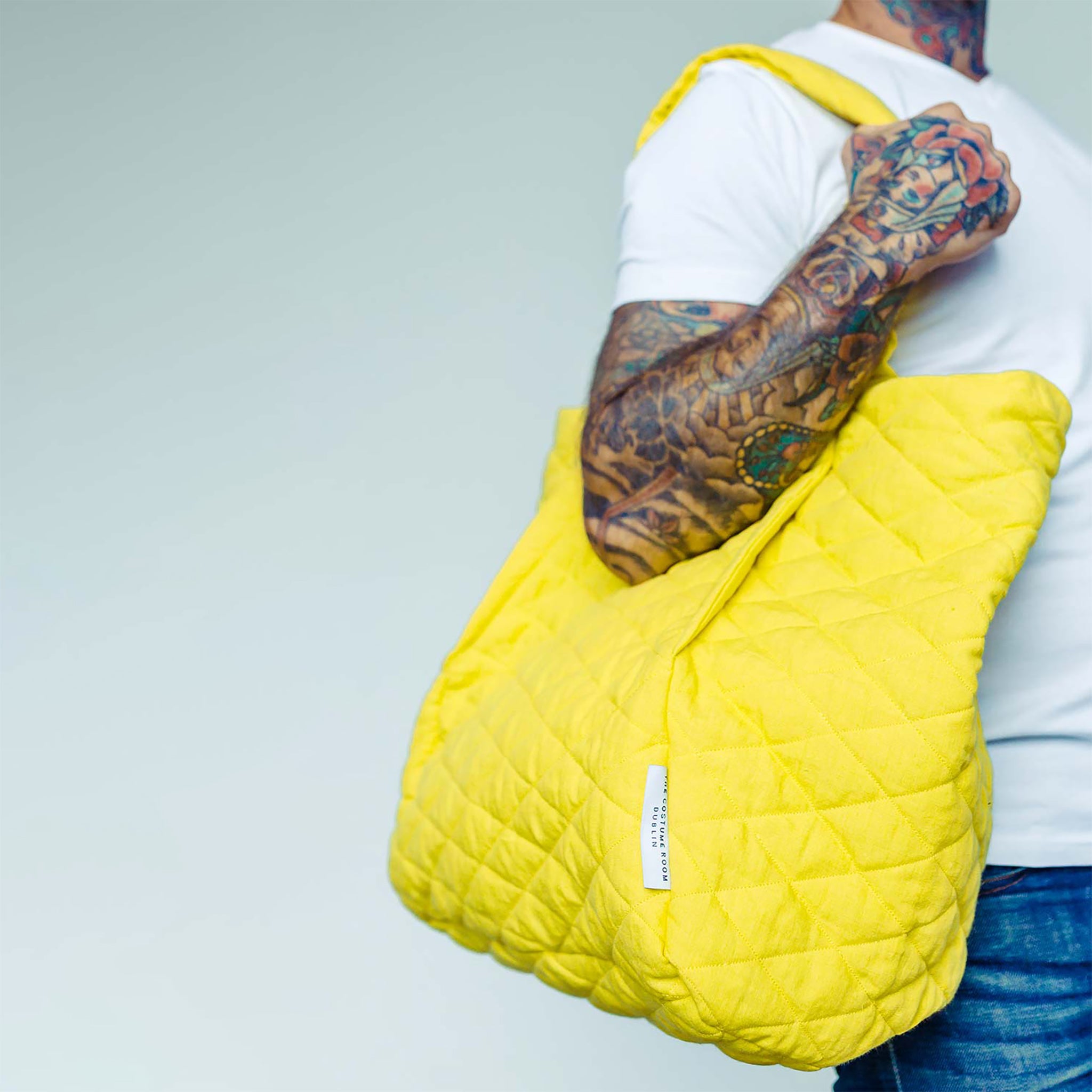 Tattooed Man wearing The Costume Room sunshine yellow Irish Linen Quilted Bag on his shoulder