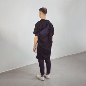Man wearing The Costume Room Navy Blue Linen Quilted Belt Bag facing the wall