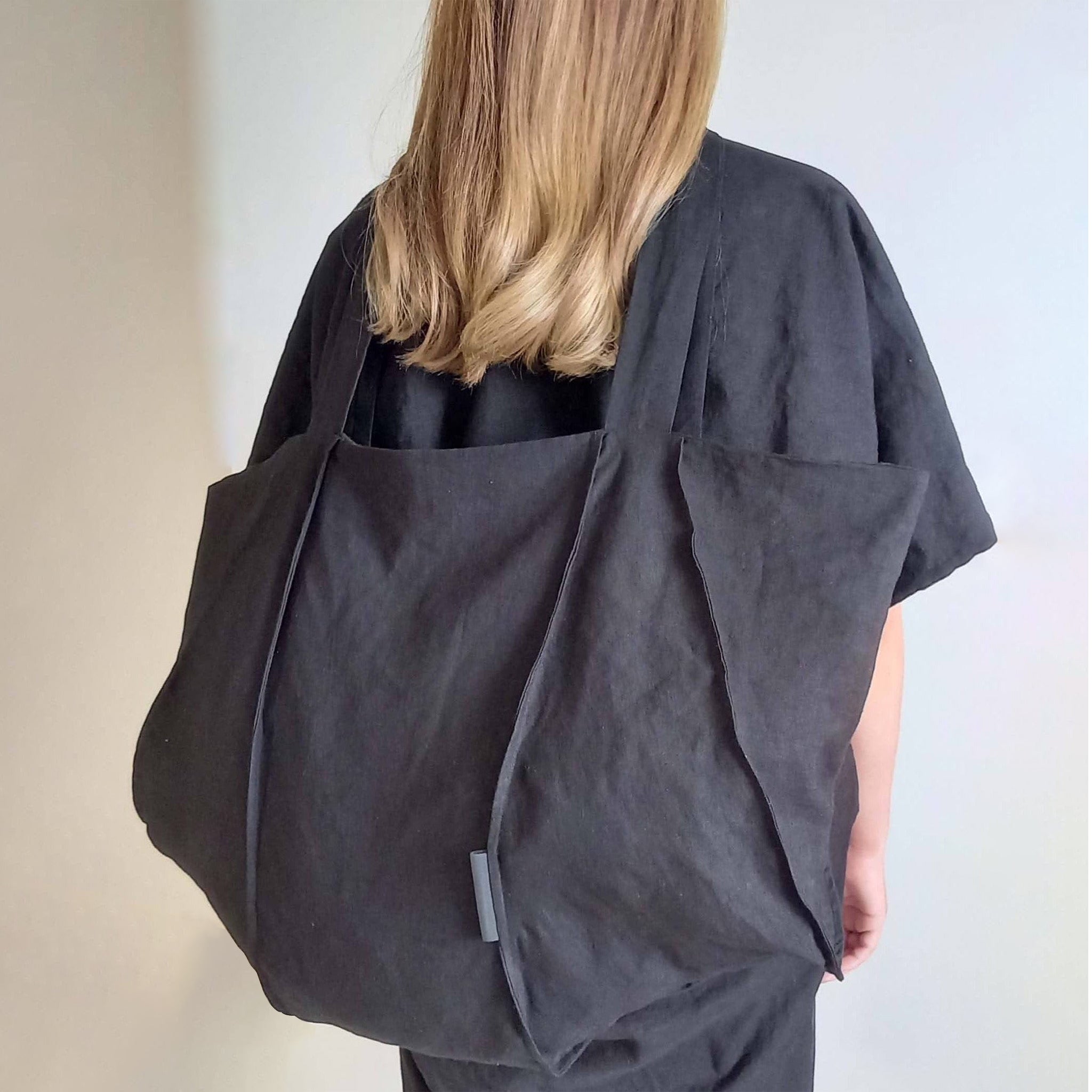 Woman wearing The Costume Room black Linen Tote Bag on her back