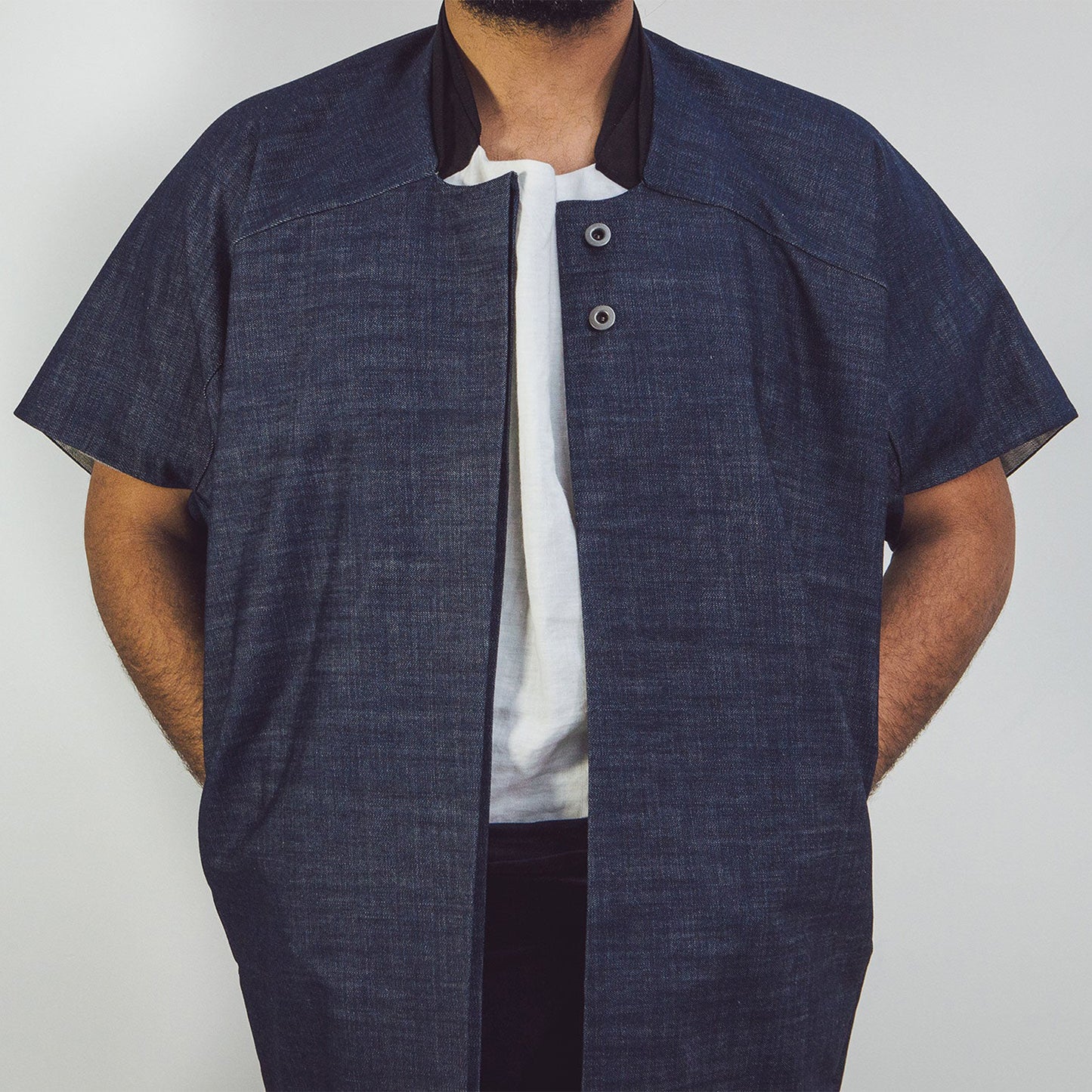 Man wearing The Costume Room Raw Organic Denim Cocoon Long Jacket with hands in pockets